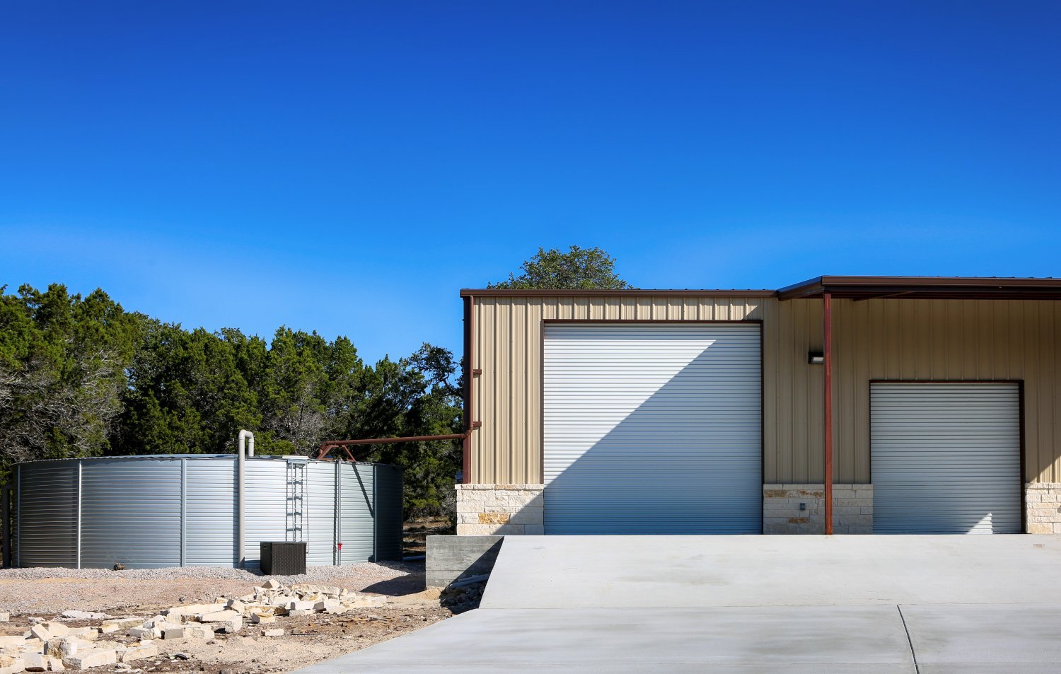 Finished metal-building barndominium home exterior under a clear blue Texas Hill Country sky